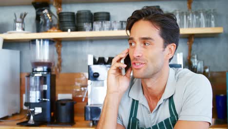el camarero está hablando por teléfono detrás del mostrador.