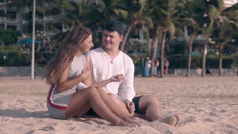 couple-sings-girl-imitates-playing-guitar-on-beach-sand