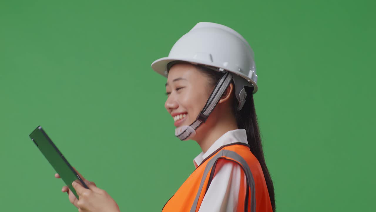 녹색 화면 배경 스튜디오에서 는 동안 태블릿을 사용하는 안전 헬을 입은 아시아 여성 엔지니어