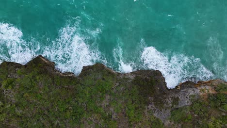 Drones-De-Arriba-Hacia-Abajo-Ascienden-Mientras-Las-Fuertes-Olas-Del-Océano-De-Un-Gran-Oleaje-Chocan-Contra-Los-Escarpados-Acantilados-De-Una-Isla-Caribeña