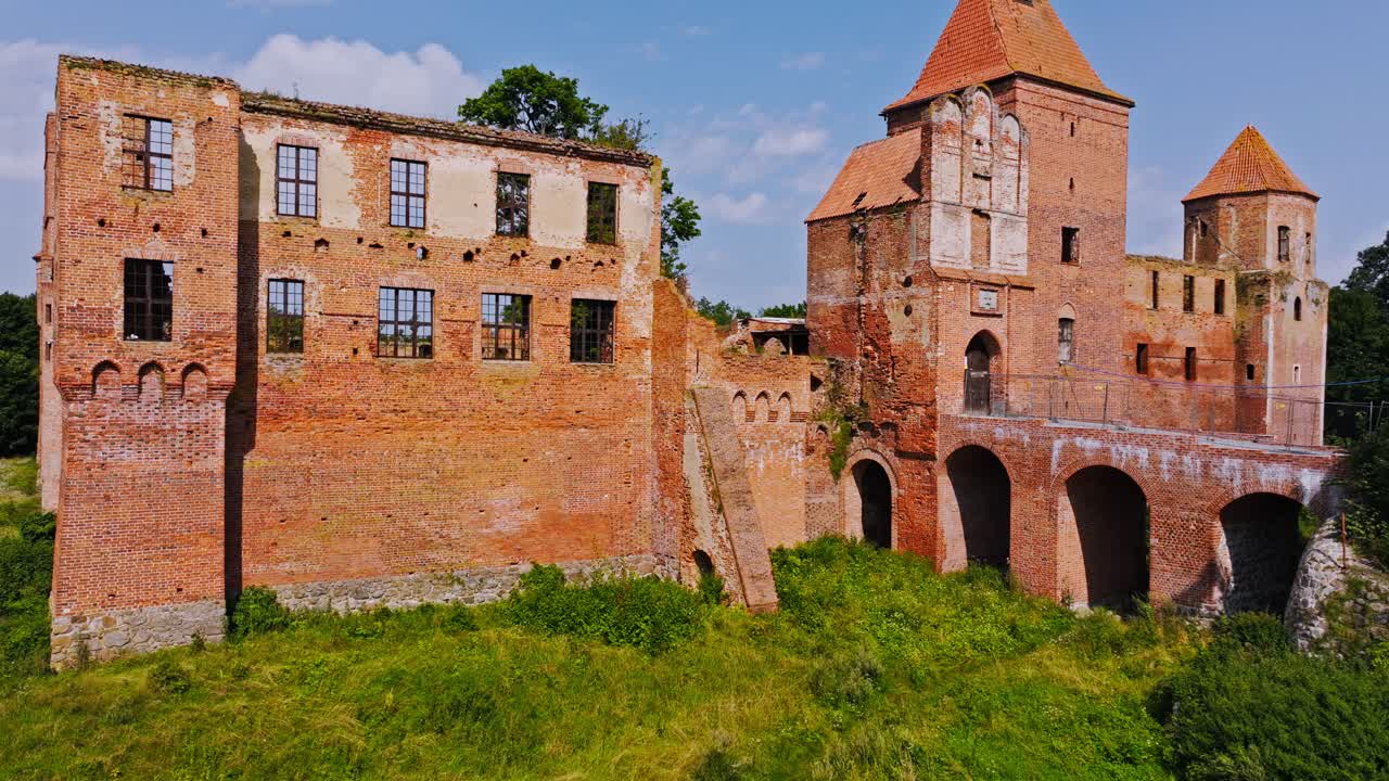 Drone vertical ascent, Szymbark Castle ruins with arches towers and brick walls