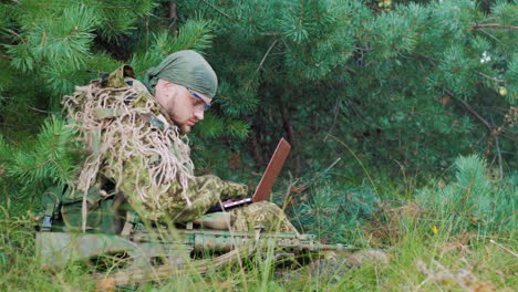 armed men in camouflage sitting in the woods it uses laptop