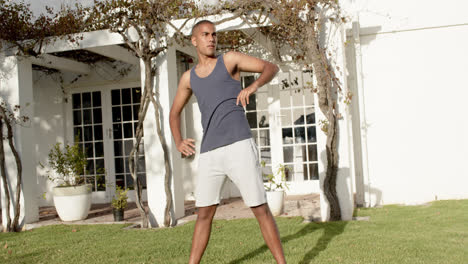 concentrado hombre biracial practicando yoga en el jardín soleado, cámara lenta