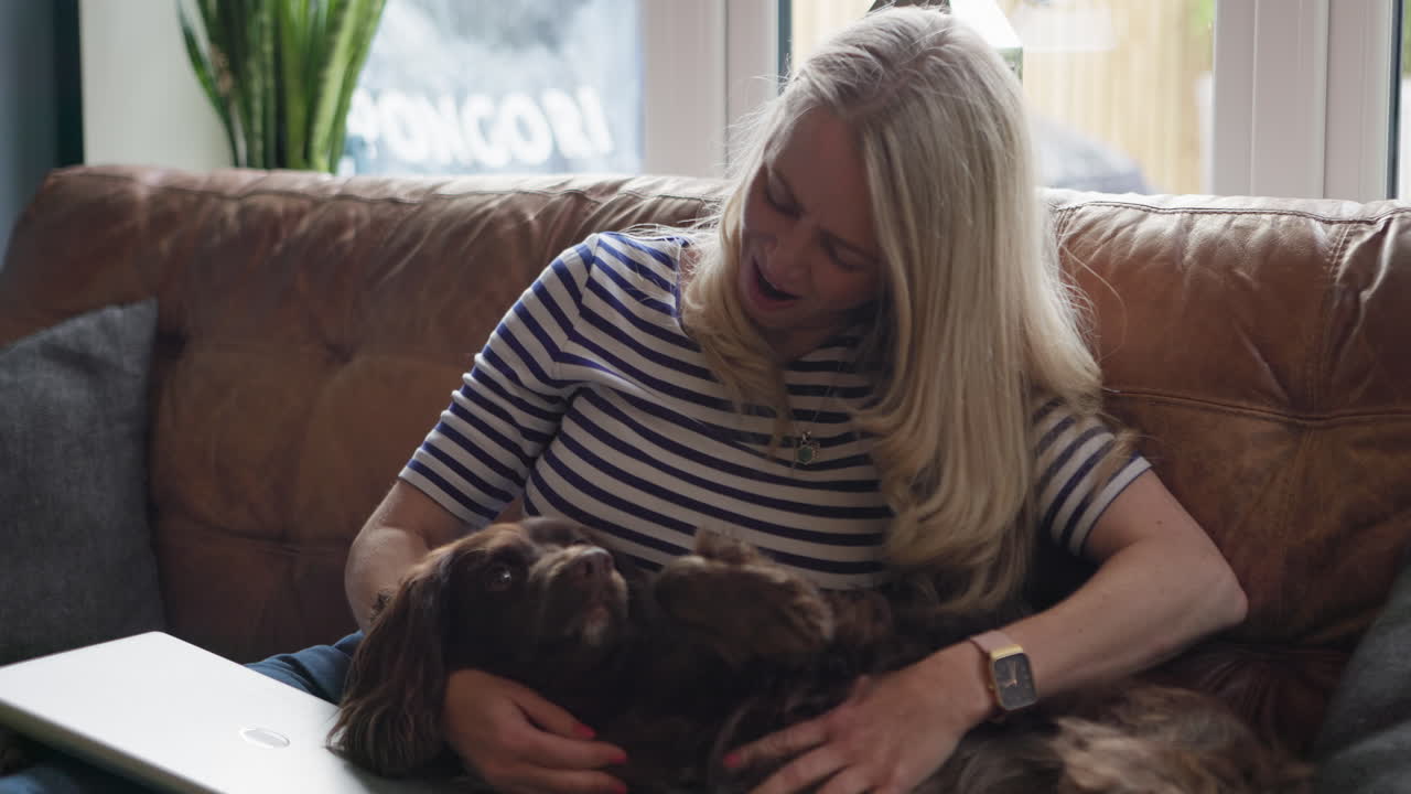 Woman petting her dog on the couch