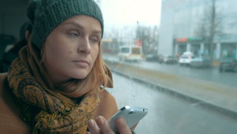 woman using phone in bus on rainy day