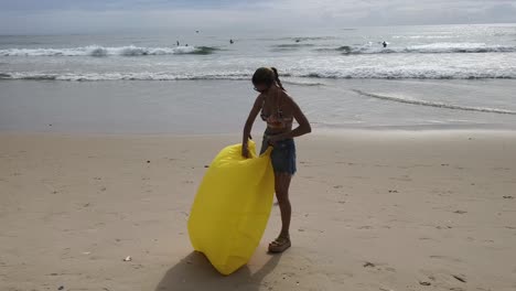 mujer empacando una silla inflable en la playa