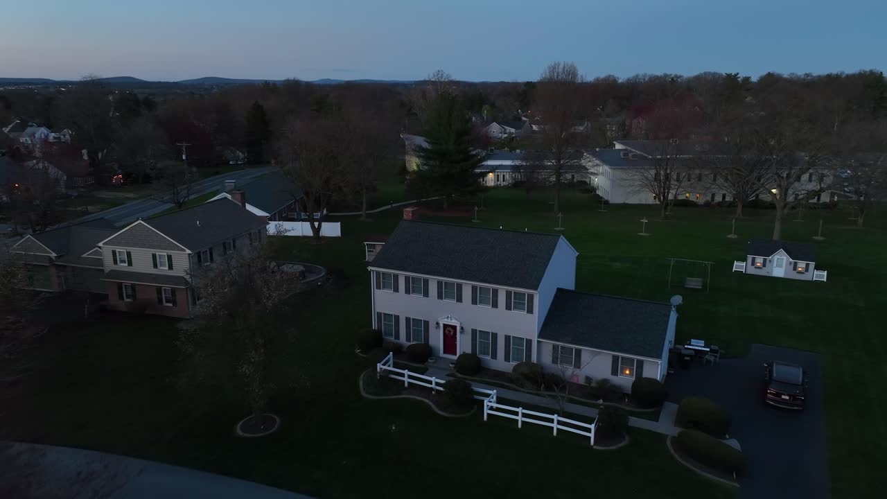 Aerial approaching shot of large single family house in suburb of american town at dusk