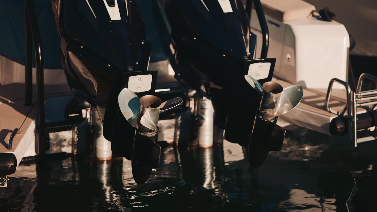 Close up of shiny metal boat propellers reflecting warm sunlight in a marina setting