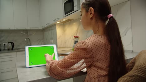 rear view of school girl doing homework online using tablet indoors