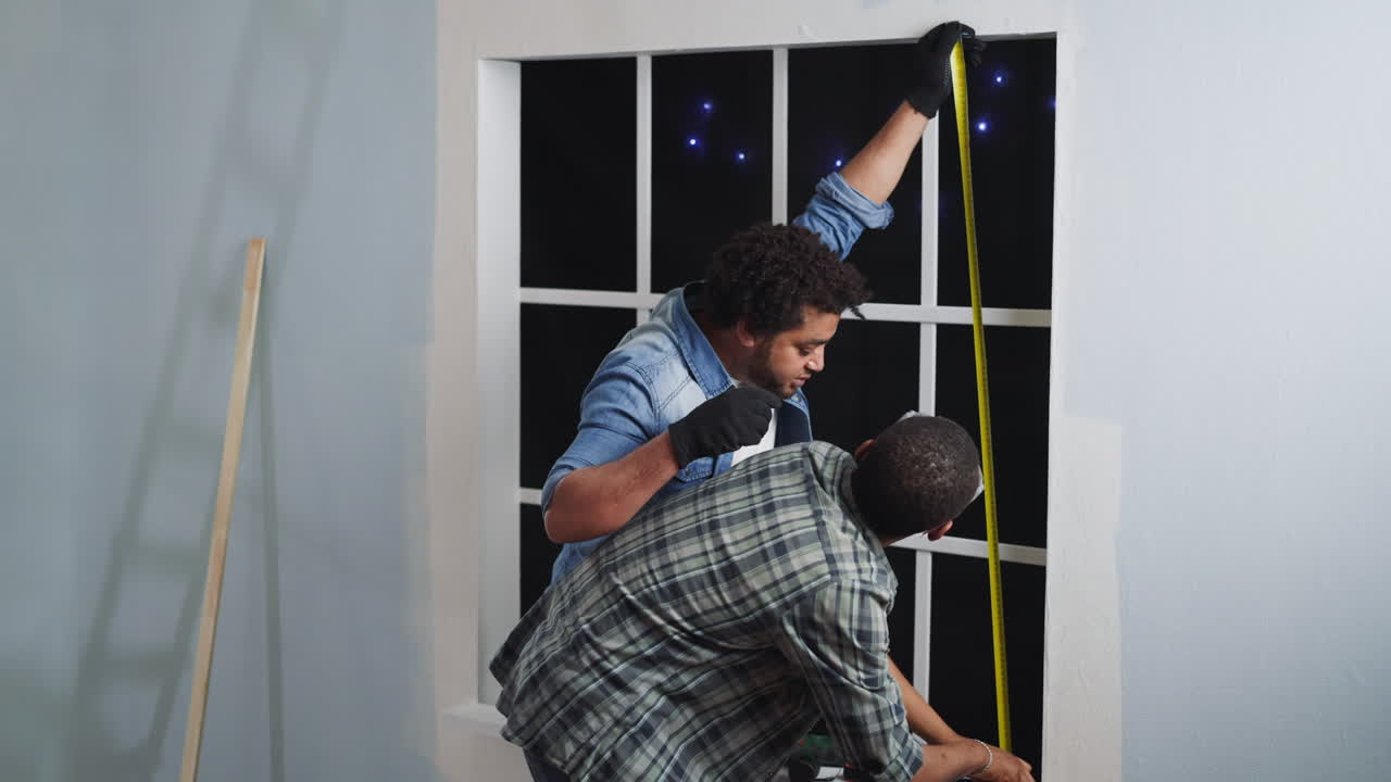 African-American builders measure window height in studio
