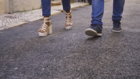 piernas de un joven y una mujer caminando por la calle.