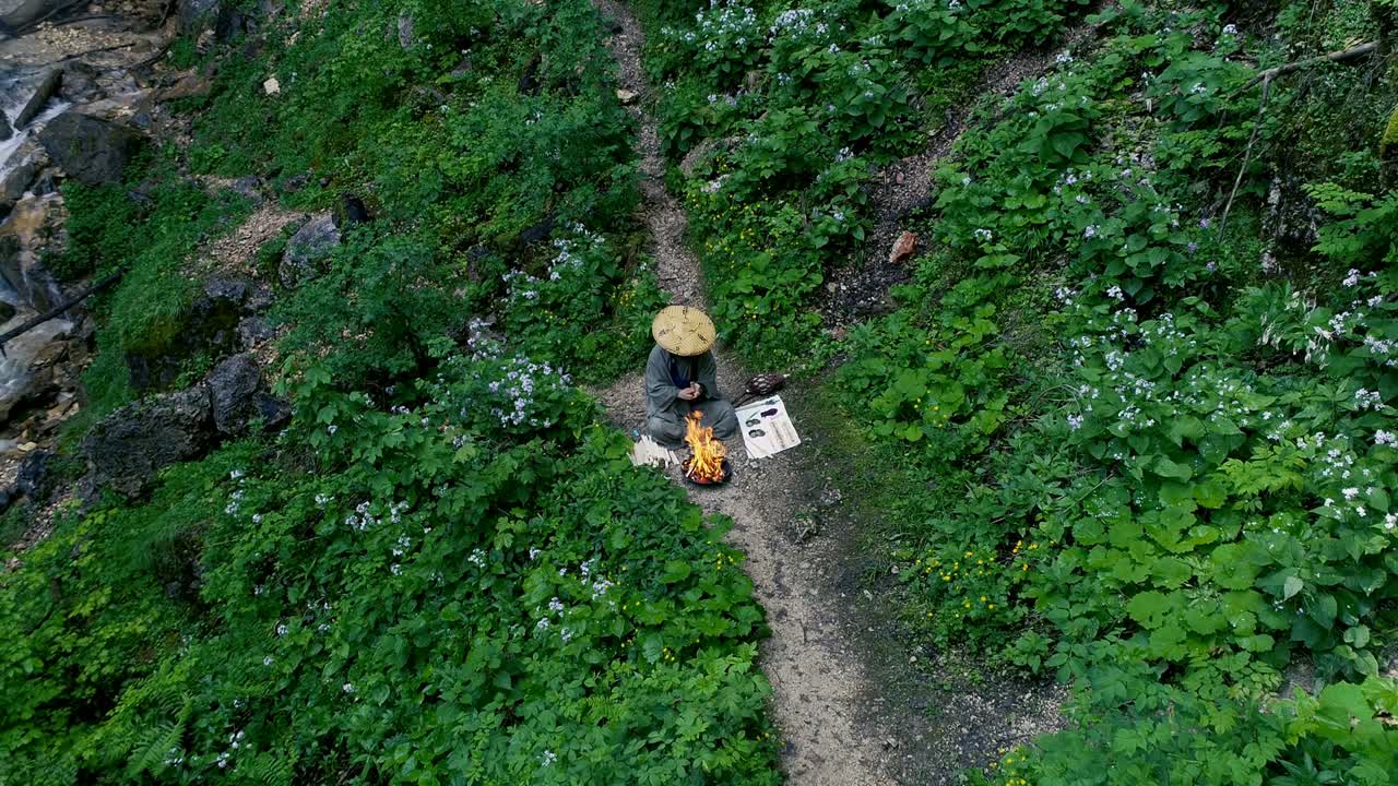 hombre con barba hace una ceremonia de fuego frente a una gran cascada
