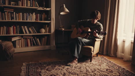 man playing guitar in a cozy living room