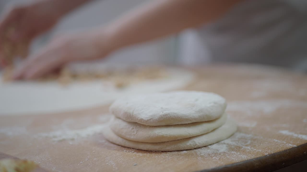 Close-up of Hands Preparing Dough on a Floured Wooden Table