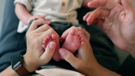 female hands hold tiny cute newborn's feet. male hand stroking little toes tenderly. close up.