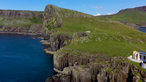 revealing drone shot of neist point lighthouse and rocky shoreline cliffs in scotland