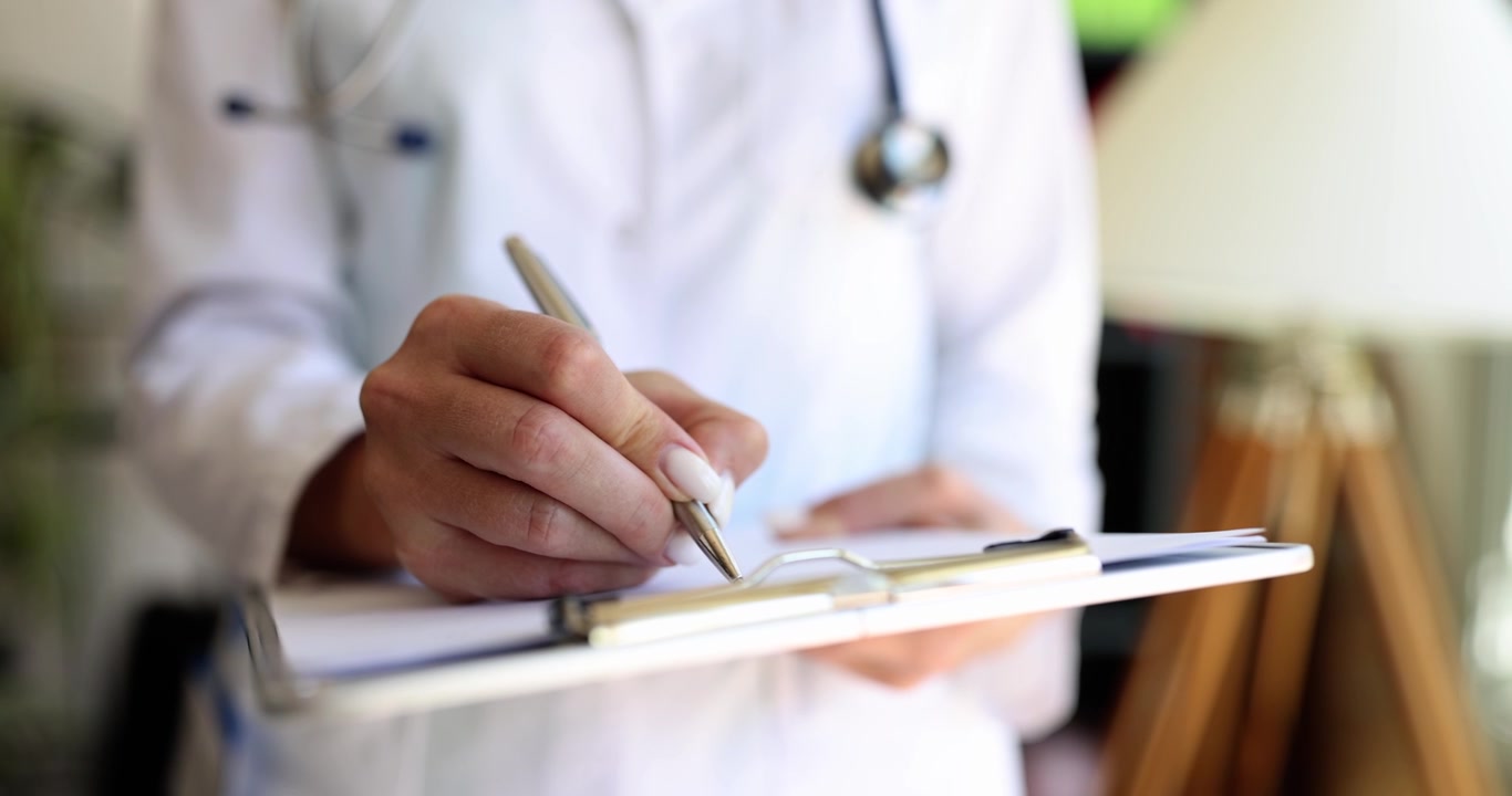 La doctora escribe con un bolígrafo en una carpeta blanca