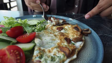 mujer comiendo una tortilla de desayuno con ensalada