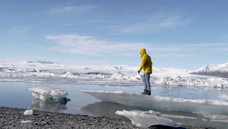 Young-Blond-Male-Traveler-Walking-on-ice-flue-in-Glacial-Lagoon-in-Iceland