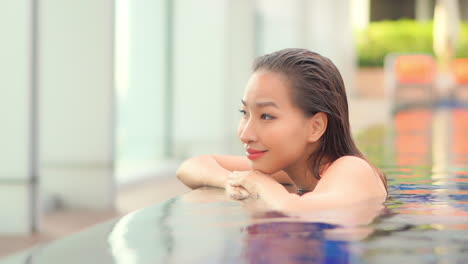 close -up a beautiful flawless woman is poised on the edge of a luxury infinity-edge swimming pool