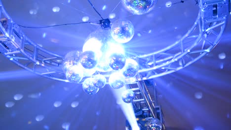 Tilt-movement-going-up-to-ceiling,-capturing-a-lot-of-mirrored-globes-reflecting-colored-lights-at-a-party