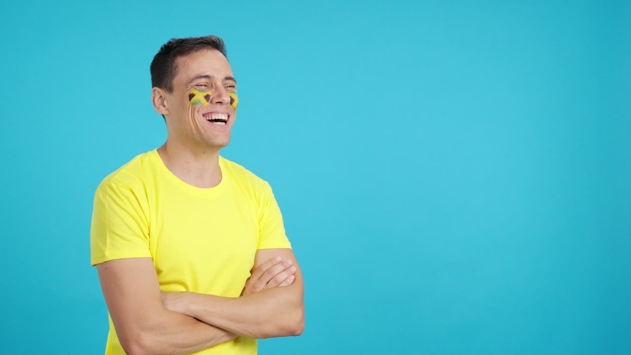 Happy man with jamaican flag painted on face looking away