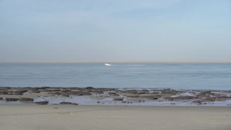 sea view from the beach. boat passing over the horizon. early morning. low tide. sunny