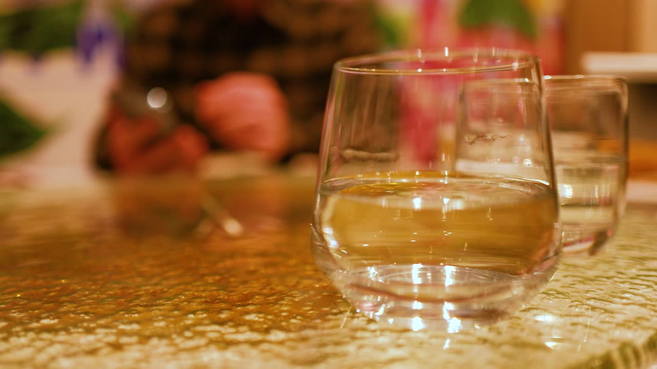 A hand pours wine into glasses on a textured table in warm lighting, creating a cozy atmosphere