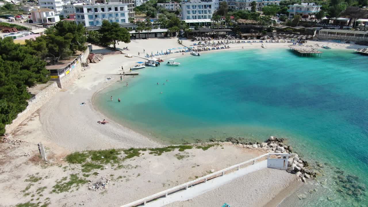 알바니아에서 드론이 하 모래 해변을 날아다니며, 푸른 크리스탈 은 물, 사람들이 수영하고 호텔, ksamil의 빛 날
