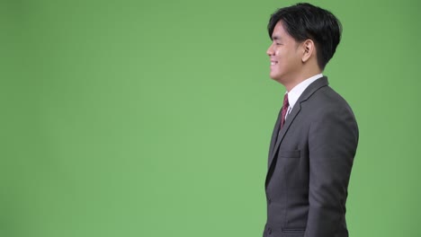 young handsome asian businessman against green background