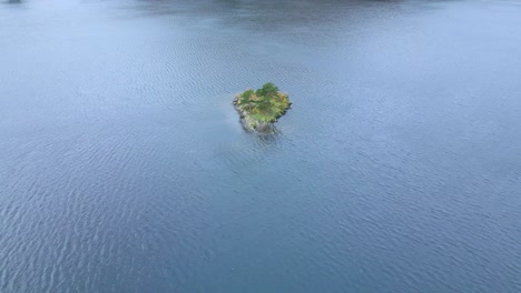 Approaching-drone-shot-of-a-small-island-in-the-midddle-of-Ullswater-Lake,-a-glacial-lake-in-Cumbria,-England-and-part-of-the-Lake-District-National-Park-in-United-Kingdom