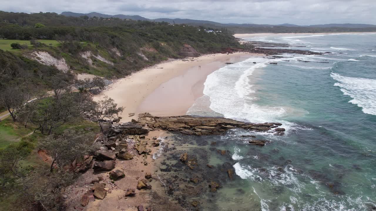 Riserva di Bartletts Beach e Headland con le onde che si infrangono a Bonny Hills, Nuovo Galles del Sud, Australia. Ripresa aerea in allontanamento.