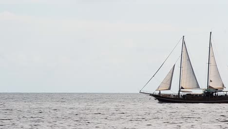 large sailboat sailing through the frame in front of a bright sky