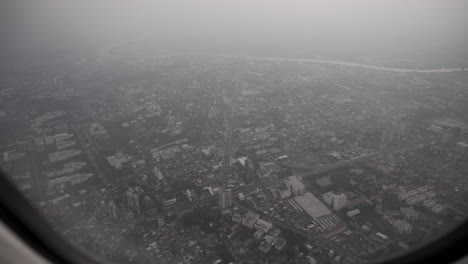 4k push in and pull out dolly shot of an airplane window from inside  taking off and gaining altitude above bangkok.