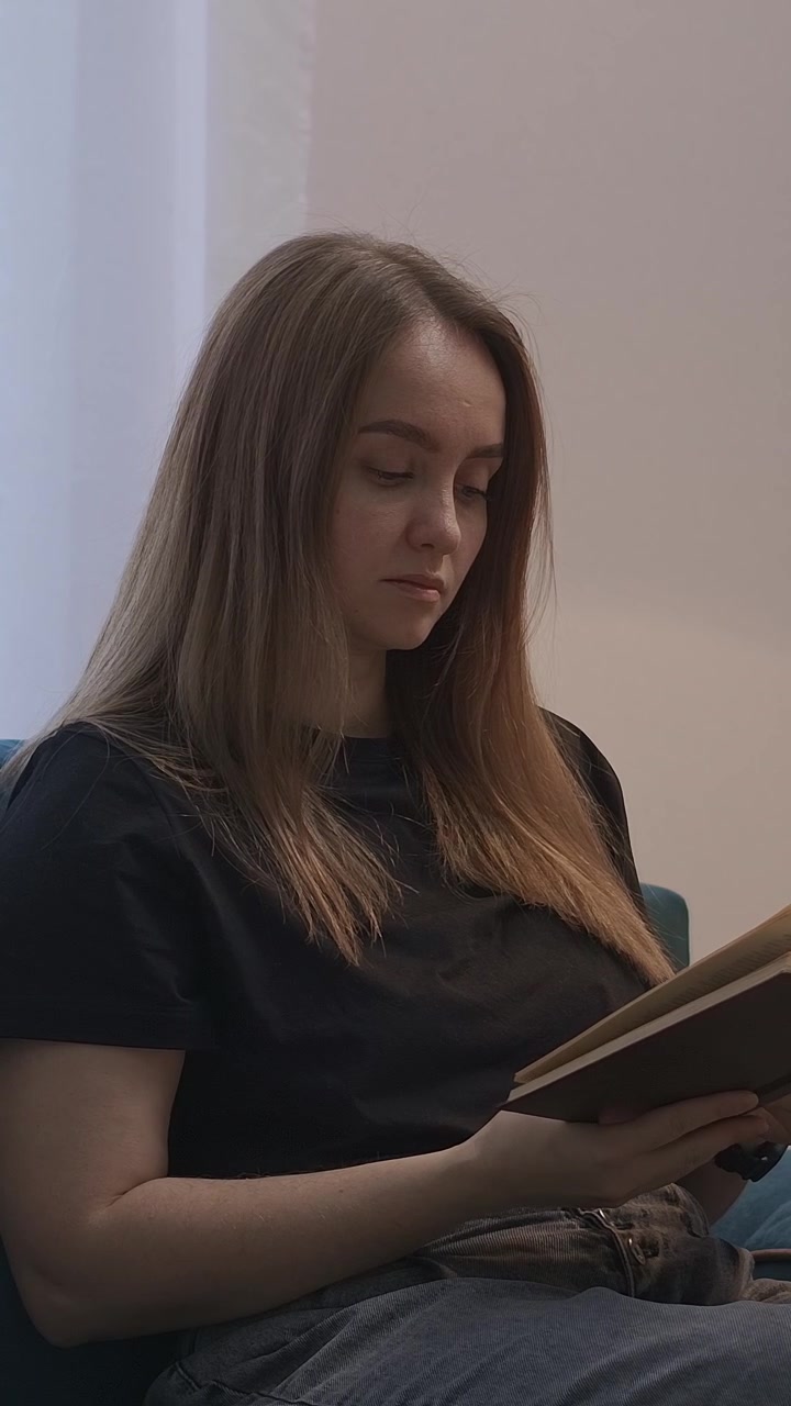 Junge Frau liest ein Buch und schaltet zu Hause eine Lampe aus.