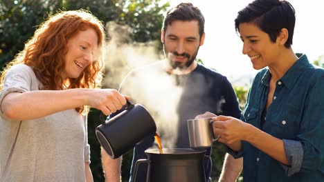 joyful friends enjoying coffee outdoors, sharing laughter and warm beverages in a beautiful natural setting with sunlight glowing around them