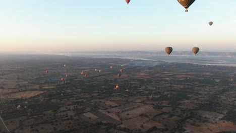 Epic-aerial-birds-eye-shot-showing-group-of-hot-air-balloons-flying-over-Bagan-plains-with-scattered-temples,-Myanmar,Asia