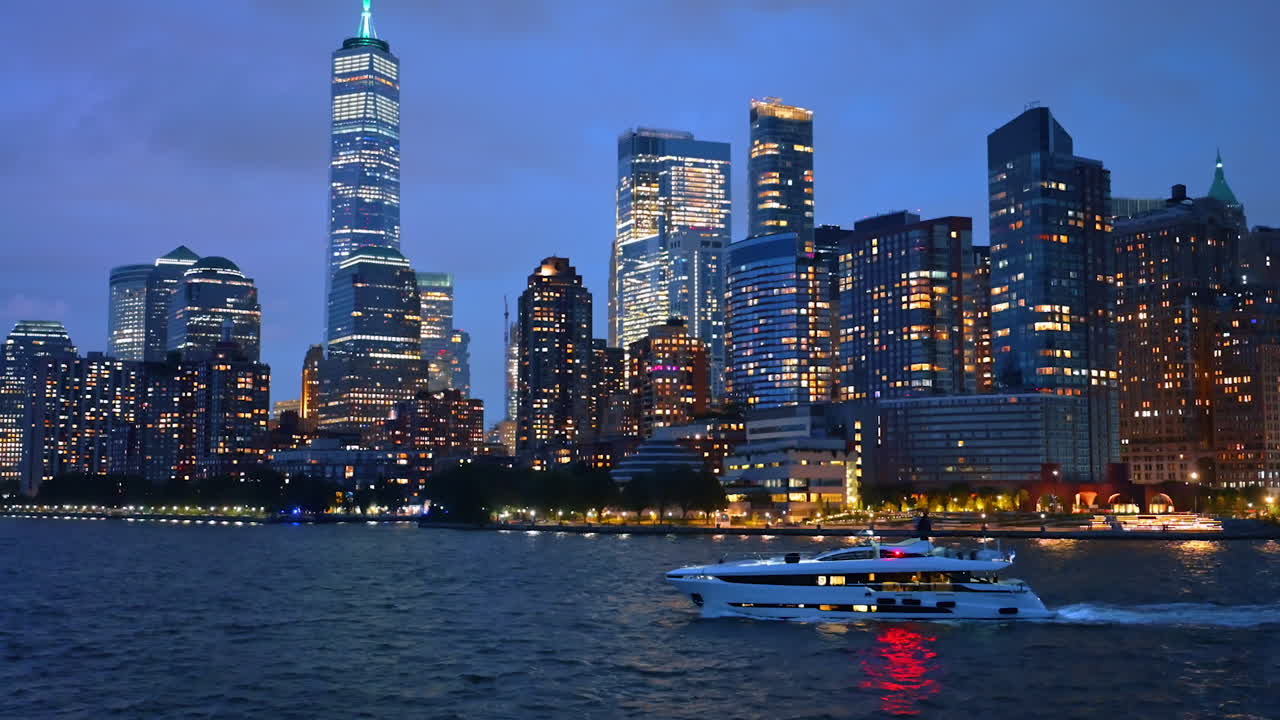 Modern white yacht moves by the riverscape of the East River. Luminous Manhattan at backdrop