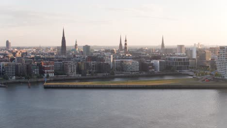 Vuelo-De-Drones-Sobre-Hamburgo-En-Una-Mañana-Soleada-De-Verano-Desde-El-Lado-Del-Puerto-Que-Muestra-La-Nueva-Casa-De-La-Filarmónica-Del-Elba-El-Michel-Y-Landungsbrücken-En-El-Fondo