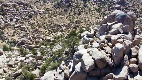 stone boulders in desert terrain in ascending tilting down drone view