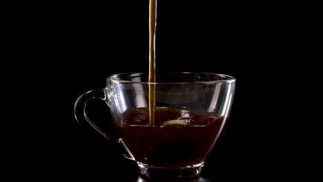 a stream of black coffee fills a transparent glass cup against a dark backdrop, highlighting the rich color and texture