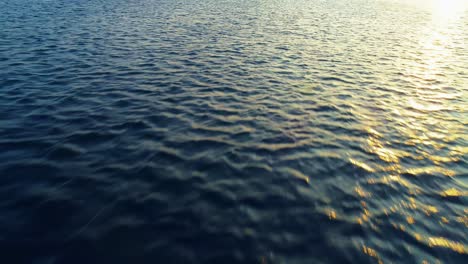 Aerial-dolly-above-golden-hour-light-dancing-on-ocean-wave-water-texture