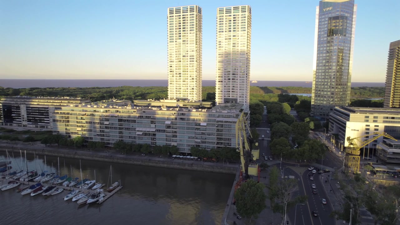 Vista aerea 4K con drone di Puerto Madero a Buenos Aires, Argentina, al tramonto. Skyline moderno riflesso sul lungomare durante l'ora d'oro nel quartiere più contemporaneo della città.