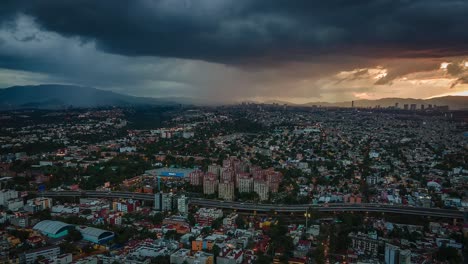 Vista-Aérea-De-Drones-De-Nubes-Oscuras-Moviéndose-Sobre-Una-Carretera-Y-El-Paisaje-Urbano,-Durante-La-Puesta-De-Sol,-En-La-Ciudad-De-México,-América---Reversa,-Seguimiento,-Tiro-De-Hiperlapso