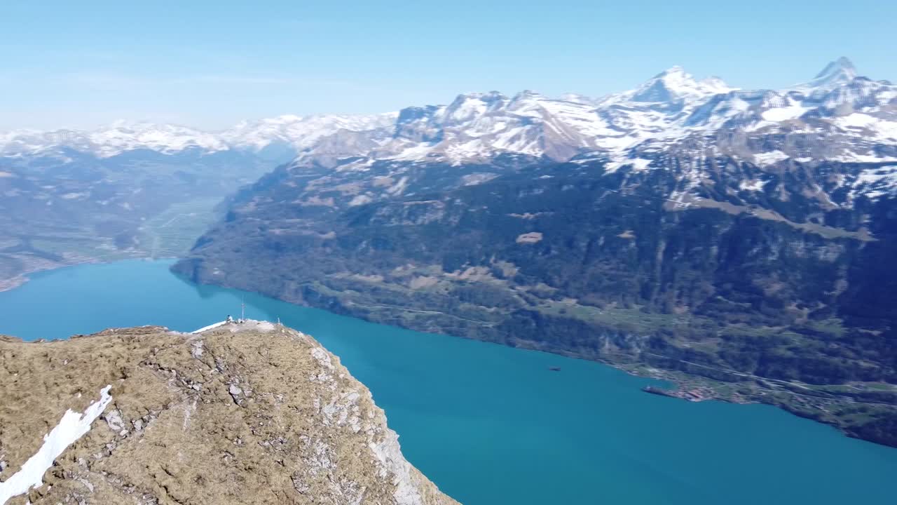 Drone flying a circle around a peak showing a amazing mountain ridge and a green lake in Switzerland