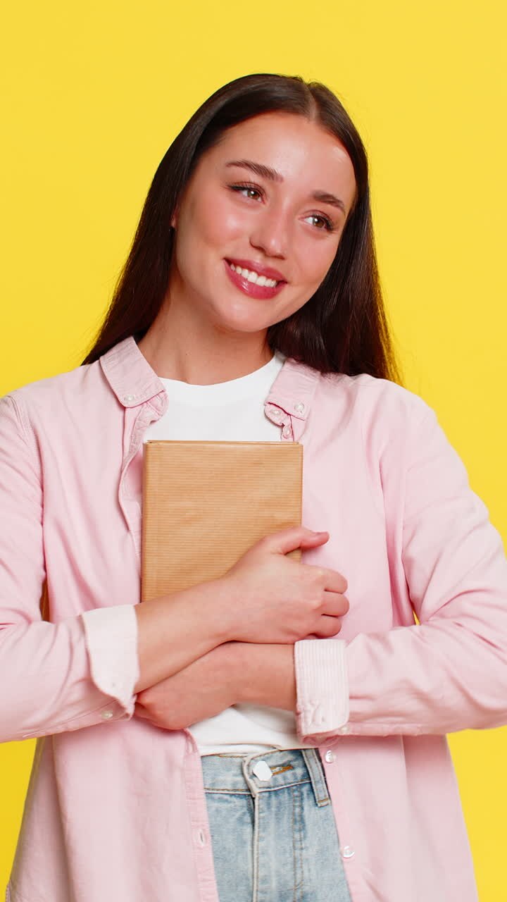 Donna sorridente che chiude un libro e lo stringe al petto soddisfatta dopo aver letto una storia emozionante
