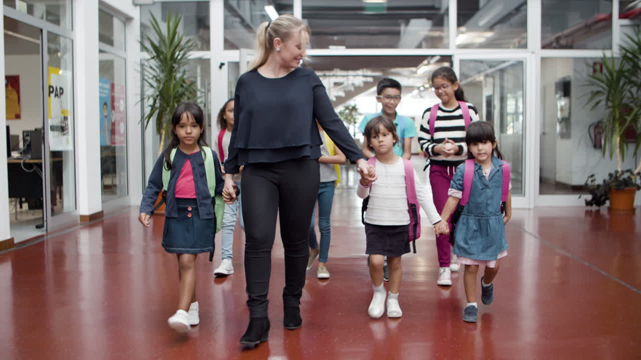 Alunos multiétnicos caminhando no corredor com uma professora