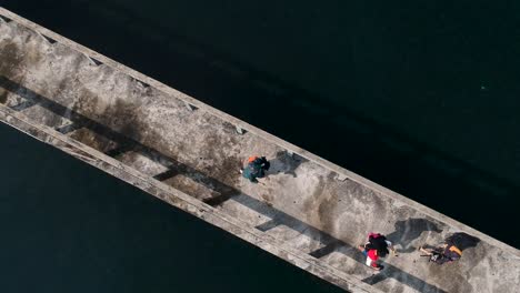 a aerial view looking done at people walking along a jetty out at sea