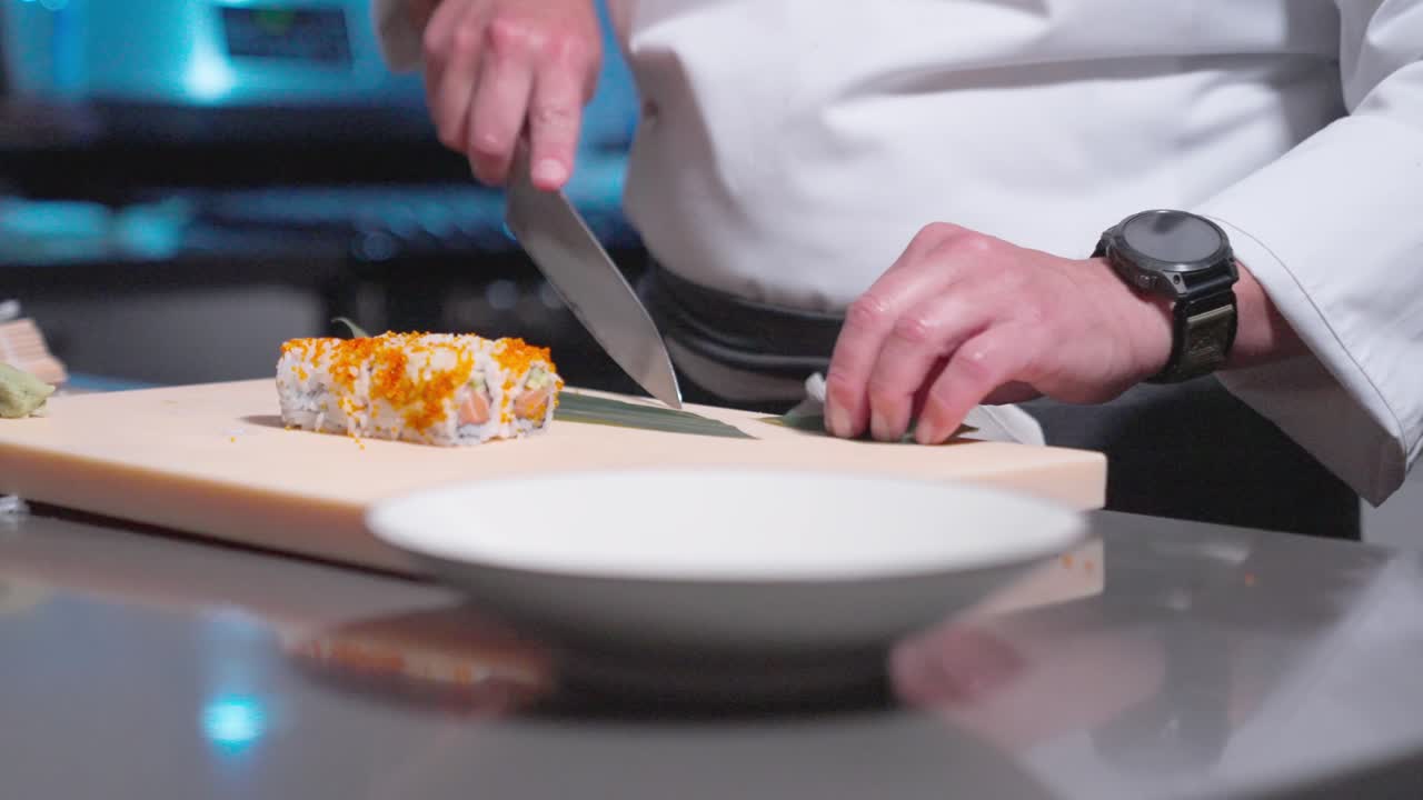 A static shot shows a sushi chef placing sushi rolls and decorative garnishes into a sushi bowl, highlighting the artful presentation. Perfect for culinary, sushi, and food prep content.