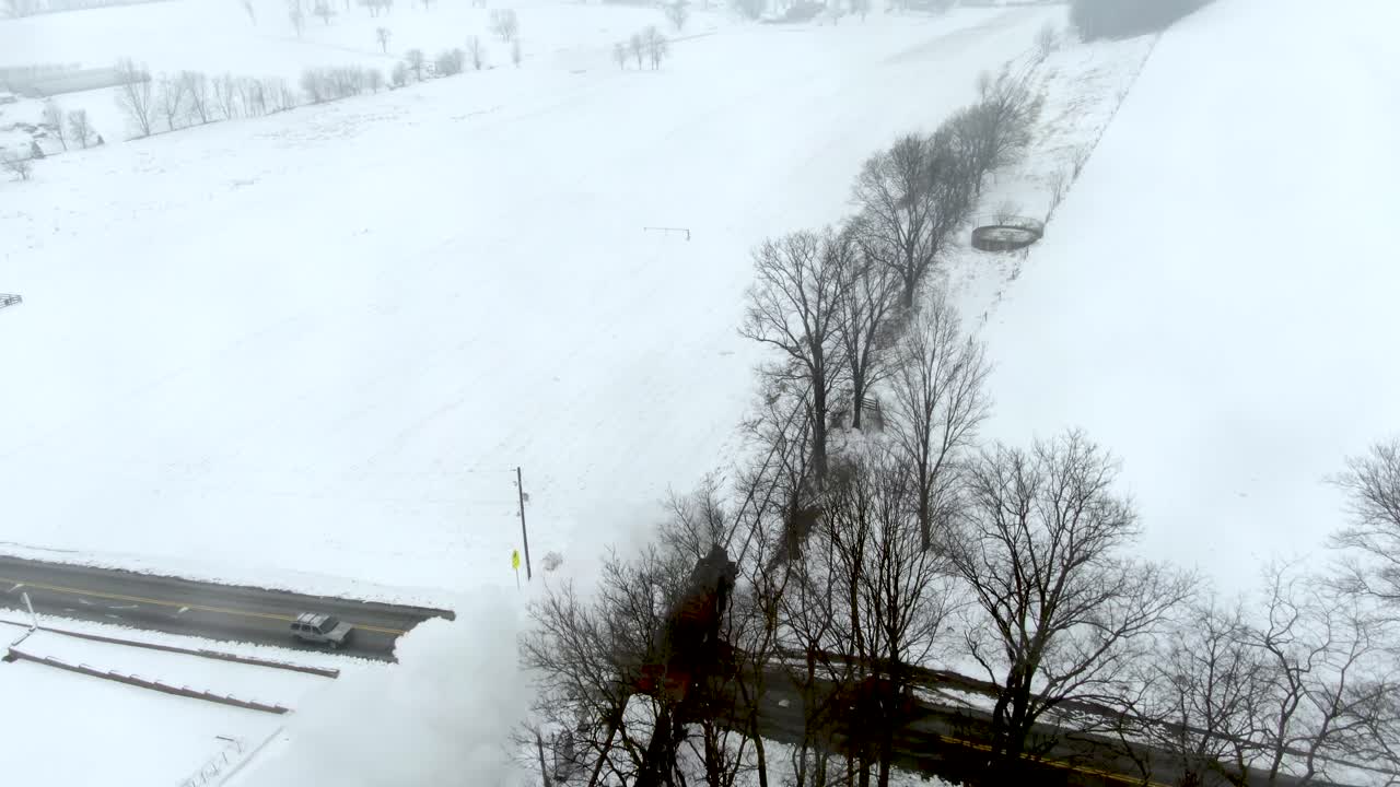 Aerial high angle of the restored 19th-century train as it passes old rural cemetery traffic is stopped at a railroad crossing as train moves on into the landscape. Strasburg Railroad Ronks, PA